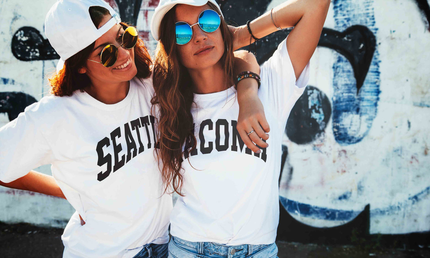 Two women wearing 'Seattle' and 'Tacoma' t-shirts