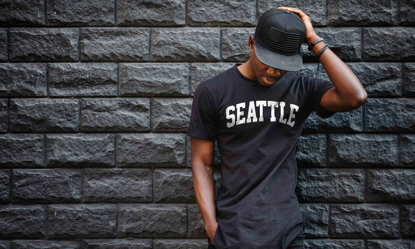 Man wearing 'Seattle' t-shirt standing against brick wall